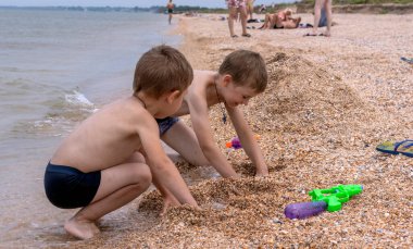 İki çocuk deniz kıyısında oynuyorlar. Çocuklar oyuncaklarla oynar. Çocuklarla seyahat.