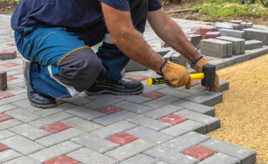Profesyonel tuğla ustaları yol, kaldırım ya da veranda için yeni kiremitler ya da levhalar döşüyorlar. Evin avlusuna gri beton döşeme döşemesi.