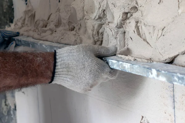 İşçi alçıyı dengeleyiciyle düzleştiriyor.