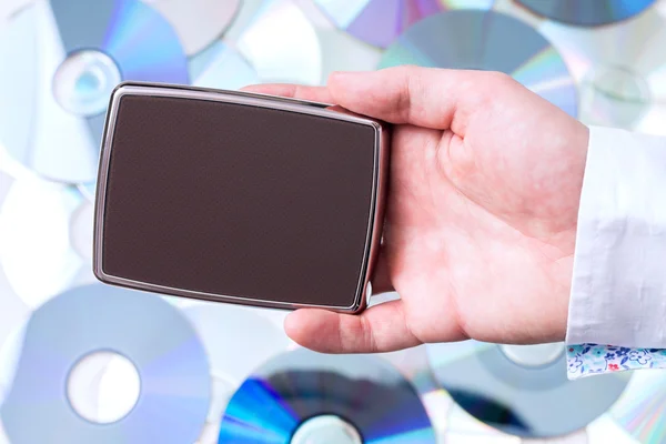 Man's hand with portable disk over CD's background. — Stock Photo, Image