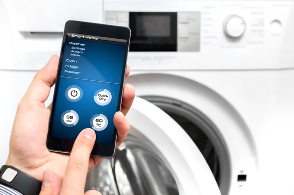 Man uses his smartphone to set up the washer — Stock Photo, Image