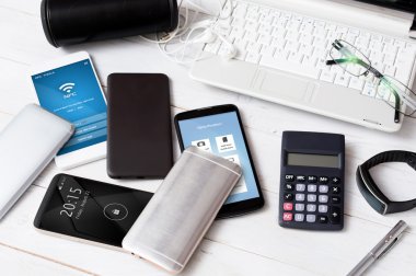 Beyaz ahşap masanın üzerinde dağınık üst seviye akıllı telefonlar. 