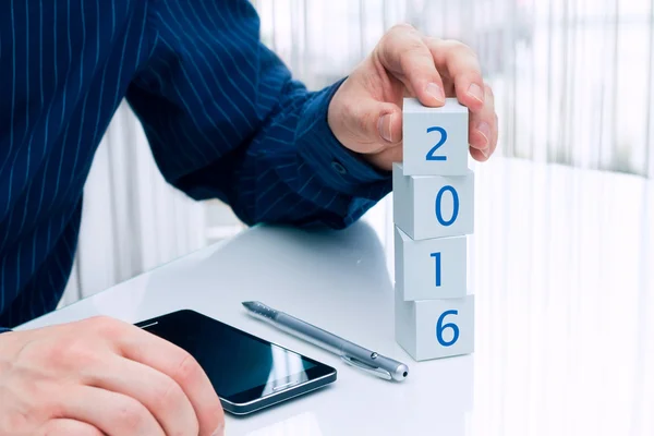 Zakenman regelen kleine blokken met datum "2016". Zakelijke pl — Stockfoto