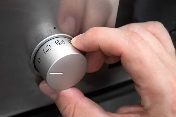 Close up of man hand setting temperature control on oven — Stock Photo, Image