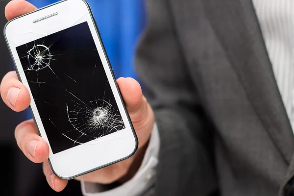 Empresário mostra smartphone quebrado com tela quebrada . — Fotografia de Stock