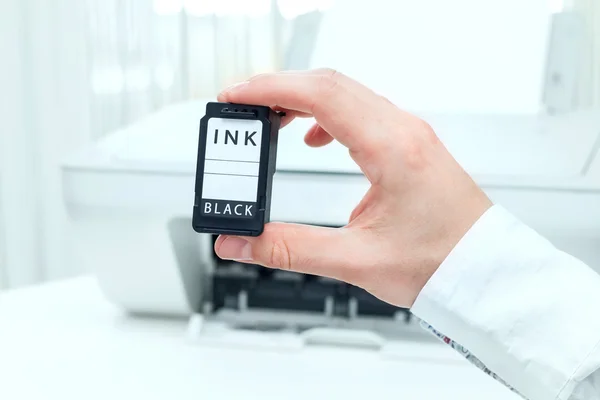Чоловік показує чорний картридж з білого принтера — стокове фото