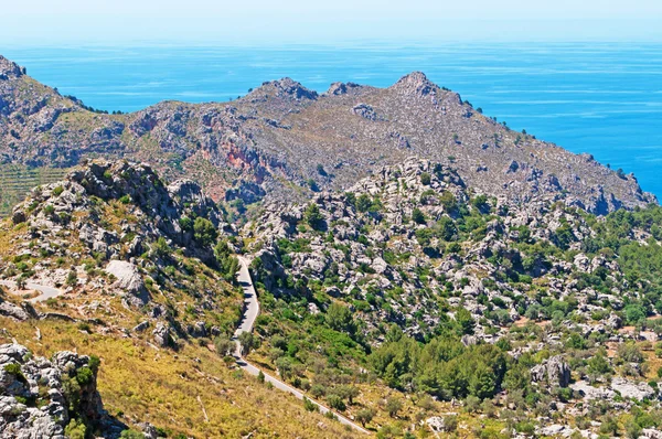 Mallorca, Baleári-szigetek, Spanyolország: a kanyargós út vezet Cala Tuent, a távoli tengerparton, Serra de Tramuntana lábánál — Stock Fotó