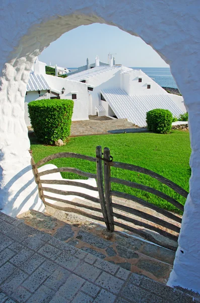 Menorca, Ilhas Baleares, Espanha: o horizonte com as casas brancas da famosa cidade de Binibeca Vell visto através de um arco — Fotografia de Stock