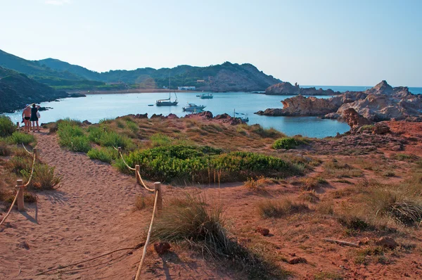 Menorca, Ilhas Baleares, Espanha: vista panorâmica do caminho, das rochas vermelhas e da areia vermelha da praia Cala Pregonda — Fotografia de Stock