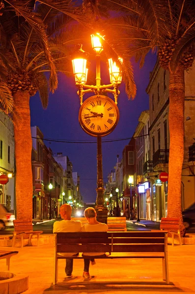 Menorca, Balearic Islands: night skyline of Ciutadella de Menorca with view of a couple on a bench in the town square of Placa d'Alfons III — Stock Photo, Image