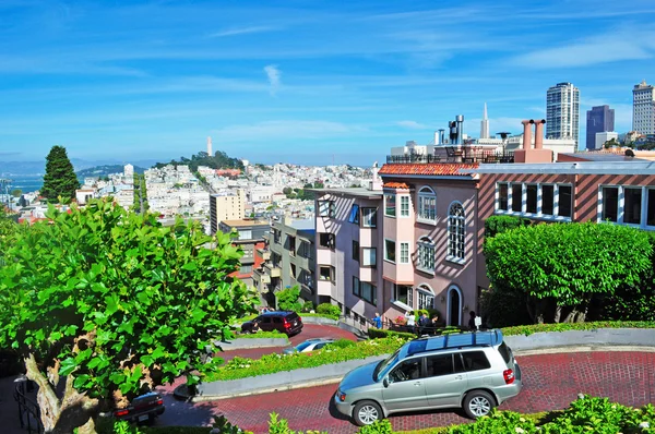 San Francisco, California, EE.UU.: skyline y coches en Lombard Street, calle este-oeste famosa por una empinada sección de una cuadra con ocho giros de horquilla, famosa por ser una de las calles más torcidas del mundo — Foto de Stock