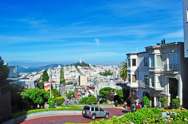 San Francisco, California, EE.UU.: skyline y coches en Lombard Street, calle este-oeste famosa por una empinada sección de una cuadra con ocho giros de horquilla, famosa por ser una de las calles más torcidas del mundo — Foto de Stock