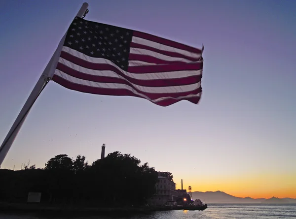 San Francisco: Amerikaanse wapperende vlag en Alcatraz island in de baai bij zonsondergang — Stockfoto