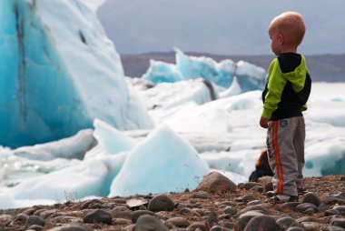 Iceland, Europe: a child looking icebergs in the Jokulsarlon glacier lagoon, a glacial lake in southeast Iceland, on the edge of the Vatnajokull National Park developed after the glacier receded from the edge of the Atlantic Ocean