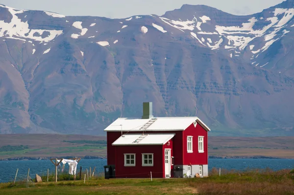 アイスランド: 洗濯乾燥に出かけるとアイスランドの田園地帯での赤い木製家 ロイヤリティフリーのストック画像