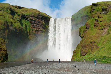 Iceland, Europe: a rainbow and view of Skogafoss waterfall, famous tourist attraction situated on the Skoga River, at the cliffs of the former coastline, in the south of the island, with a width of 25 metres and a drop of 60 metres