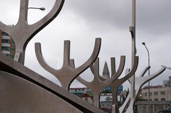 Reykjavik, Island, Europa: Hallgrimskirkja, kyrkan Hallgrimur symbol för staden, sedd genom Solfar, kallad Sun Voyager, den 1990 skulptur av Jon Gunnar Arnason ligger framför Nordatlantiska oceanen — Stockfoto