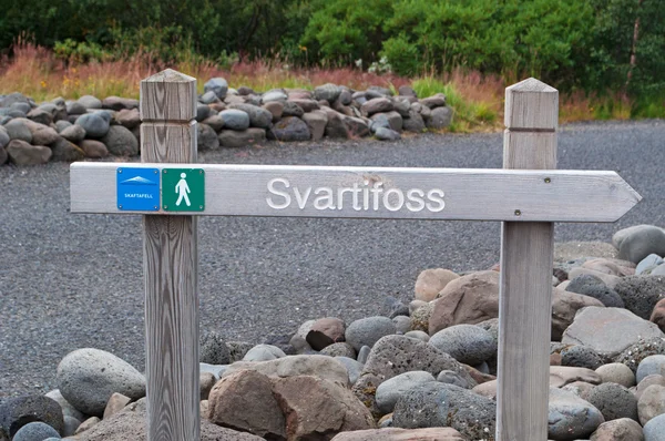 アイスランド、ヨーロッパ:スヴァルティフォスの滝、ブラックフォールズ、スカフタフェルの有名な観光名所、バトナジョクル国立公園内の歩道上の木製の看板、暗い溶岩柱に囲まれています — ストック写真