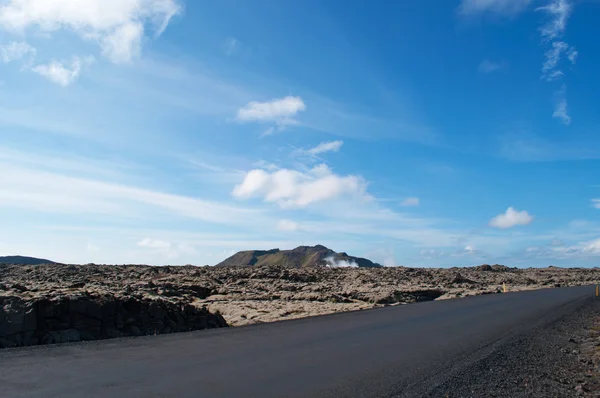 IJsland, Europa: luchtfoto van het adembenemende woestijnlandschap met een weg en lavavelden in Reykjanes schiereiland, regio in het zuidwesten van IJsland met grote oude lavavelden van zwarte rotsen bedekt met een dikke groene tapijt van mos — Stockfoto