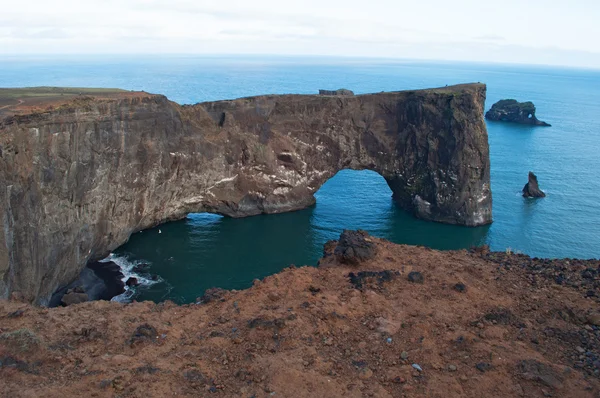 Island, Europa: Luftaufnahme des gigantischen schwarzen Lavabogens, der im Meer auf der Landzunge von Dyrholaey steht und die Bucht von Vik i Myrdal überblickt, dem südlichsten Dorf der Insel, einer der wichtigsten Touristenattraktionen des Südens — Stockfoto