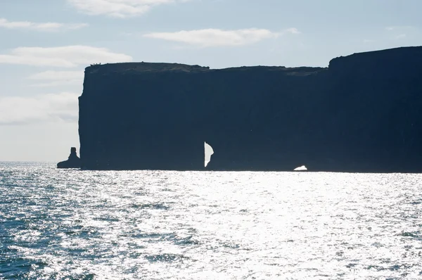 Islandia, Europa: vista aérea del gigantesco arco negro de lava que se encuentra en el mar sobre el promontorio de Dyrholaey y con vistas a la bahía de Vik i Myrdal, el pueblo más al sur de la isla, uno de los principales atractivos turísticos del sur —  Fotos de Stock