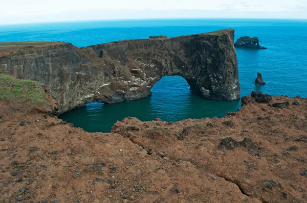 Iceland, Europe: aerial view of the gigantic black arch of lava standing in the sea on the promontory of Dyrholaey and overlooking the bay of Vik i Myrdal, the southernmost village of the island, one of the main tourist attractions of the south — Stock fotografie