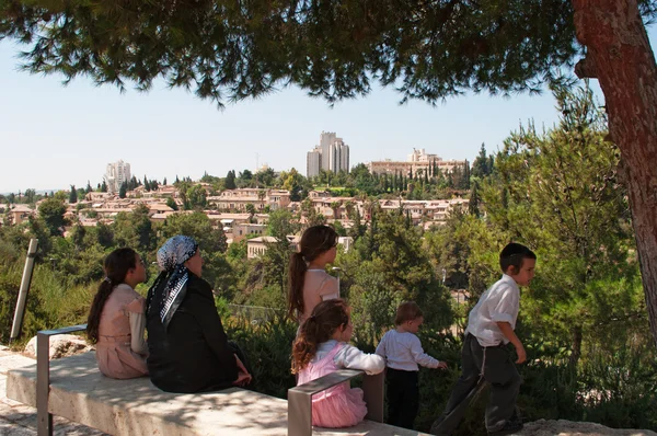 Israel: a family of Orthodox Jews seated in the shade enjoying the view of Jerusalem — Stock Photo, Image