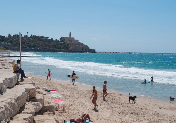 Tel Aviv, Israel, Middle East: people on the beach and the panoramic view of the skyline of the old city of Jaffa with the bell tower of St. Peter 's Church, a Franciscan church built in 1654 on the top of the oldest part of Tel Aviv Yafo — стоковое фото