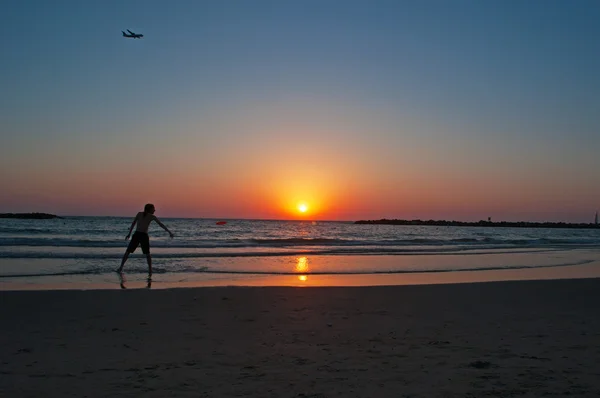 Tel Aviv, Izrael, Blízký východ: chlapec hrající frisbee na pláži při západu slunce — Stock fotografie