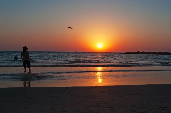 Tel Aviv, Izrael, Blízký východ: chlapec hrající frisbee na pláži při západu slunce — Stock fotografie