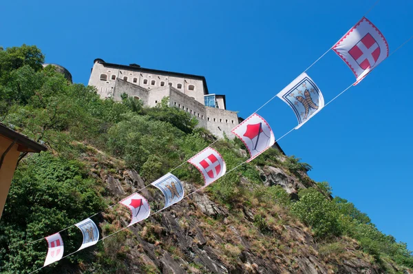 Bard, Aosta údolí (Valle d'Aosta), Itálie, Evropa: vlajky a pohled na pevnost Bard, slavný opevněný komplex domu Savoy, postavený v 19. století používá jako umístění v 2015 pro film Avengers Age of Ultron — Stock fotografie