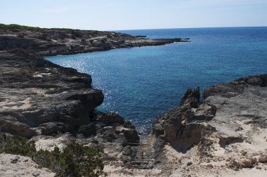 Formentera, Balear Adaları, İspanya: ahşap geçit tekneler ve Calo des Mort, Platja (veya Playa) de çarpıcı sahil kesiminde bir koyda kayaları çıkarın