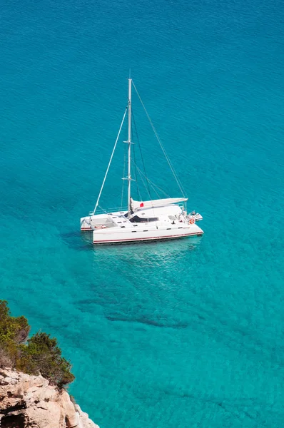 Formentera, Ilhas Baleares, Espanha: vista para o maquis mediterrânico com um catamarã no mar Mediterrâneo — Fotografia de Stock