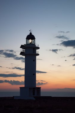 Formentera, Balearic Islands, Spain: view of Es Cap de Barbaria Lighthouse at sunset, beacon built in 1972 and located at the far southern tip of the island on the top of a rocky cliff clipart