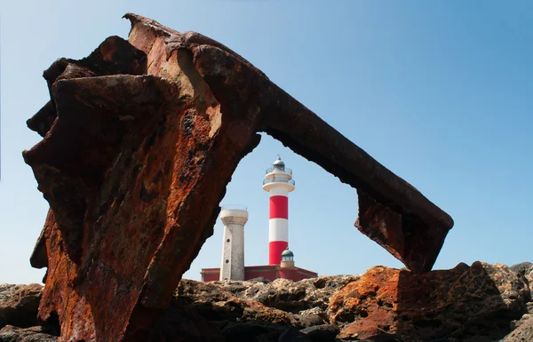 Fuerteventura, Islas Canarias, España: rocas negras con Faro de Toston (faro de Toston o faro de El Cotillo), un faro activo en Punta de la Ballena abierto en 1897, visto a través de los restos oxidados del naufragio de un barco — Foto de Stock