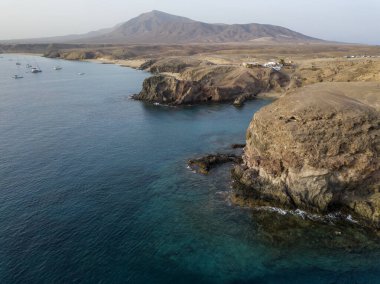 Lanzarote, İspanya ve Kanarya 'nın sivri kıyılarının havadan görünüşü. Yollar ve toprak yollar. Adayı keşfetmek için yürüyüş rotaları. Kumsalda yüzüyor. Atlantik Okyanusu. Papagayo