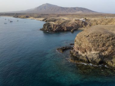 Lanzarote, İspanya ve Kanarya 'nın sivri kıyılarının havadan görünüşü. Yollar ve toprak yollar. Adayı keşfetmek için yürüyüş rotaları. Kumsalda yüzüyor. Atlantik Okyanusu. Papagayo