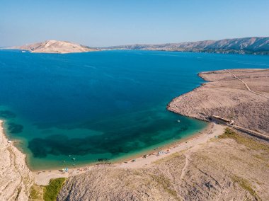 Hırvatistan 'ın Metajna kentindeki Pag Adası' ndaki Rucica plajının hava manzarası. Deniz yatağı ve plaj yukarıdan görünüyor, banyolar, rahatlama ve yaz tatilleri. Hırvat kıyılarının önyargıları ve uçurumları.