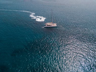 Kanarya, İspanya 'nın Lanzarote adasının kıyıları yakınlarında, içinde insan bulunan ve denizde yüzen katamaranın havadan görünüşü. Jet ski denizde gösteri yapıyor.