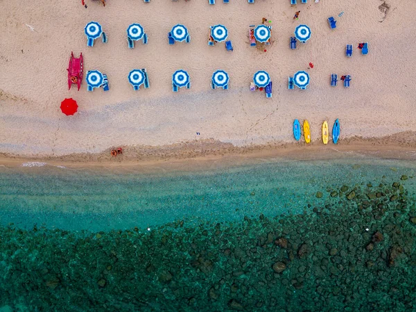 Aerial view of a beach and umbrellas. Tropea, Calabria, Italy. Parghelia. Overview of seabed seen from above, transparent water. Swimmers, bathers floating on the water. Lido La Grazia — Stock Image Aerial View Beach Umbrellas Tropea Calabria Italy Parghelia Overview Seabed Stock Image