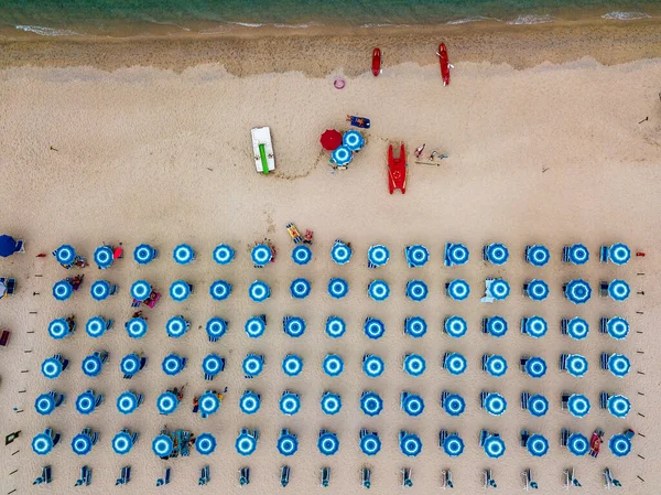 Aerial view of a beach and umbrellas. Tropea, Calabria, Italy. Parghelia. Overview of seabed seen from above, transparent water. Swimmers, bathers floating on the water. Lido La Grazia — Stock Image Aerial View Beach Umbrellas Tropea Calabria Italy Parghelia Overview Seabed Stock Photo