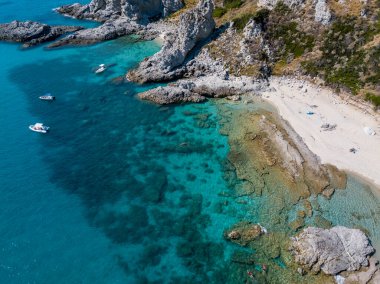 Şeffaf bir denizde yüzen demirli teknelerin havadan görüntüsü. Tüplü dalış ve yaz tatili. Capo Vaticano, Calabria, İtalya. Promontory 'de. Praia Odak Noktası ve Ficara Sahili.