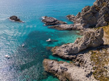 Şeffaf bir denizde yüzen demirli teknelerin havadan görüntüsü. Tüplü dalış ve yaz tatili. Capo Vaticano, Calabria, İtalya. Promontory 'de. Praia Odak Noktası ve Ficara Sahili.