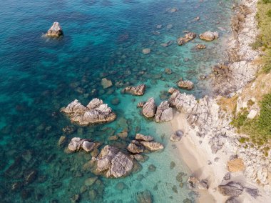 Plajın ve şemsiyelerin havadan görünüşü. Tropea, Calabria, İtalya. Parghelia. Yukarıdan görünen deniz yatağının genel görünümü, şeffaf su. Yüzücüler, suda yüzen banyocular. Vardanello sahilleri ve kayalıkları