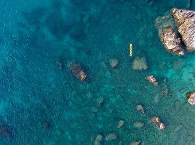 Şeffaf bir denizde yüzen bir kanonun havadan görüntüsü. Denizde yıkanır. Parghelia, Tropea, Calabria, İtalya. Dalış ve yaz tatilleri. İtalyan kıyıları, plajları ve kayalıkları. Vardanello Sahili