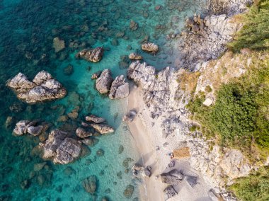 Plajın ve şemsiyelerin havadan görünüşü. Tropea, Calabria, İtalya. Parghelia. Yukarıdan görünen deniz yatağının genel görünümü, şeffaf su. Yüzücüler, suda yüzen banyocular. Vardanello sahilleri ve kayalıkları