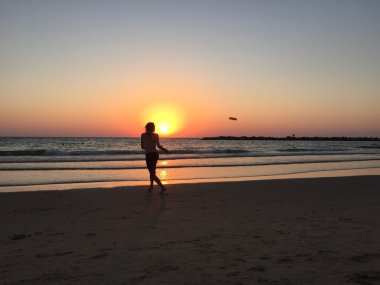 Tel Aviv, İsrail, Ortadoğu: frisbee kumsalda gün batımında oynayan bir çocuk