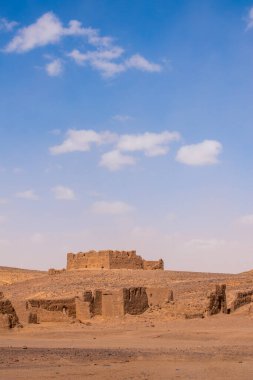 Merzouga, Morocco, Africa: panoramic road in the Sahara desert with view of the ruins of an ancient and abandoned nomadic village near the fossil mines in the Black Mountain area