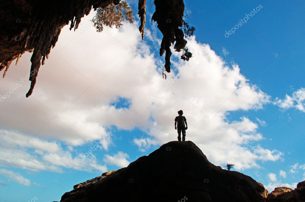 Socotra, Yemen, Middle East: the backlight silhouette of a man standing on a rock at the entrance of the Hoq Cave the protected area of the Homhil Plateau on the island of Socotra, Unesco world heritage site since 2008 for its biodiversity