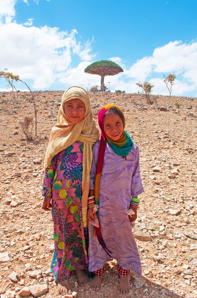 Сокотра, Йемен, Ближний Восток: маленькие девочки и дерево крови дракона в лесу деревьев крови дракона в каньоне Шибхам, охраняемая территория плато Диксам в центральной части острова Сокотра
